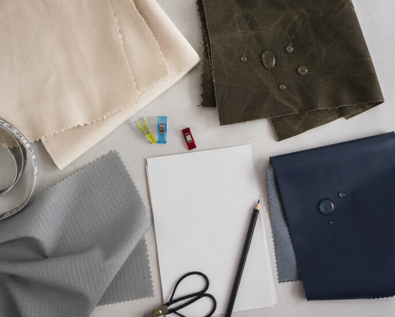 Fabric selection flat lay with cotton canvas, waxed canvas, ripstop nylon, and vinyl coated fabric samples for water protection comparison
