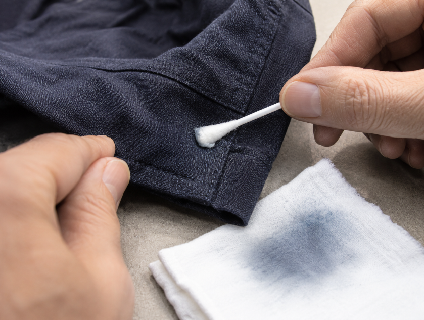 Hidden-area colorfastness test on dark dyed fabric using a white cloth to check for dye transfer