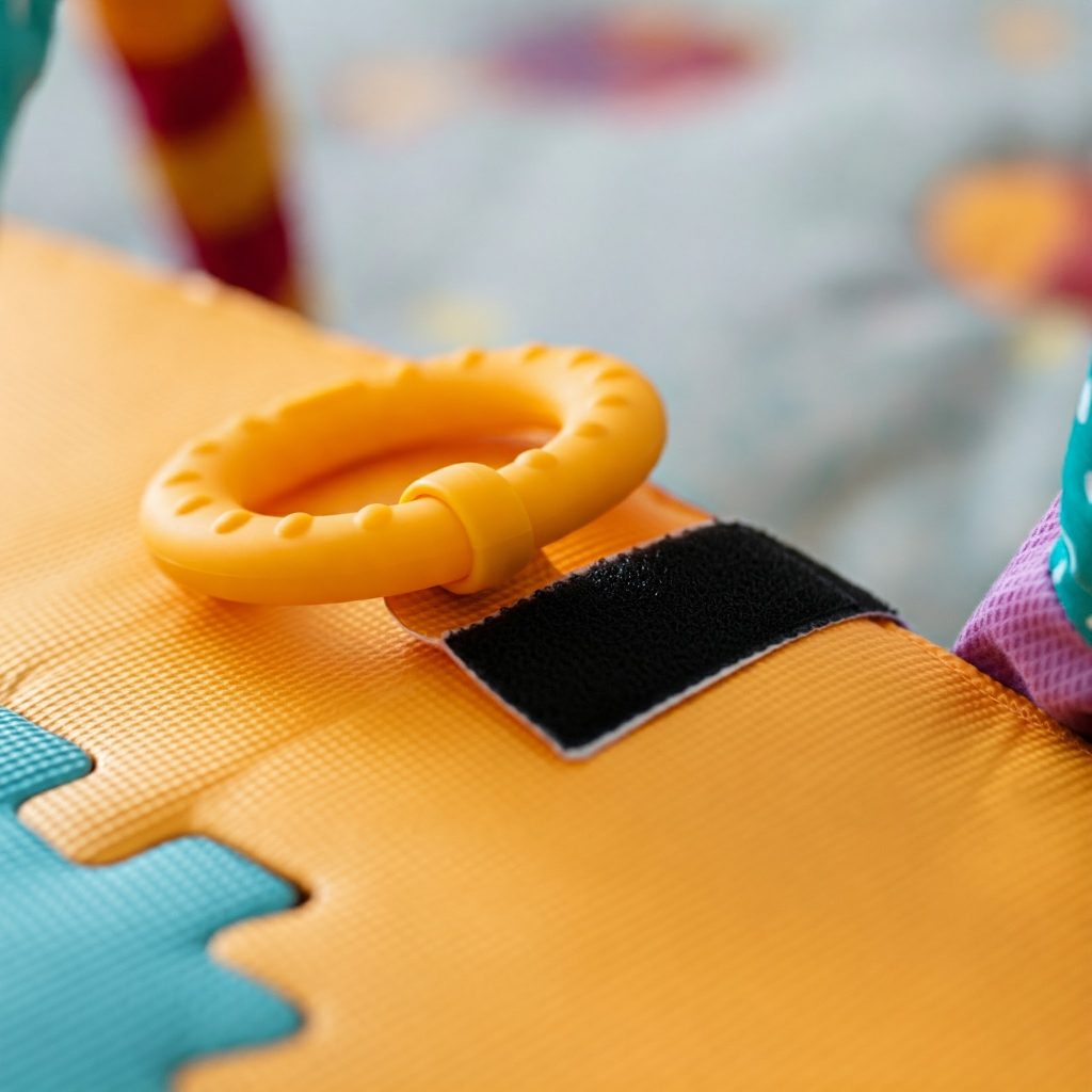 Close-up of silent hook and loop tape being used to attach a toy to a play mat