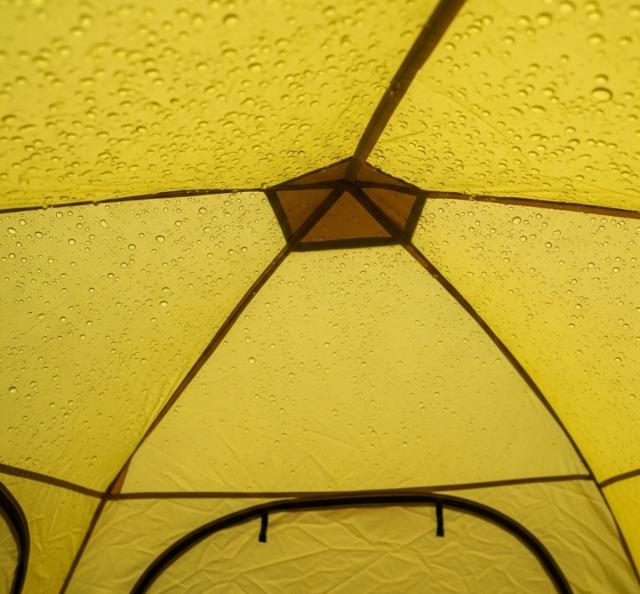 The interior ceiling of a polyester tent covered with water droplets, showing a clear example of heavy condensation caused by a lack of fabric breathability.